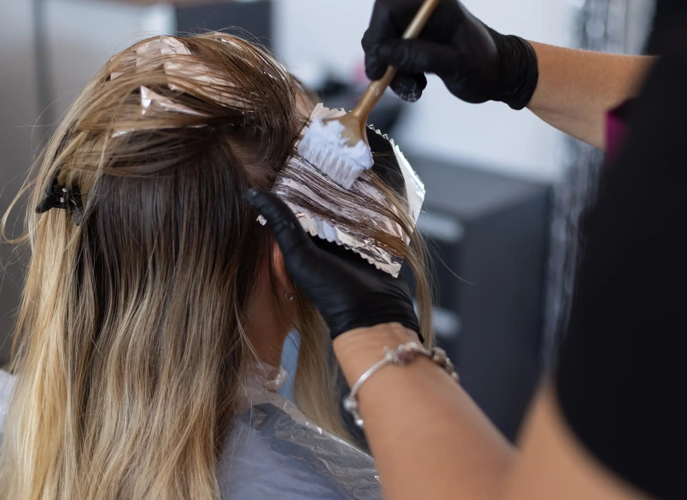Friseur beim Auftragen von Farbe auf das Haar eines Kunden