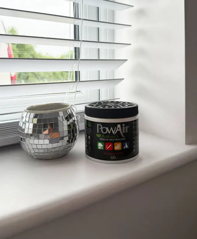 Ein PowAir Gel Geruchsentferner steht auf einer Fensterbank neben einer kleinen Deko-Vase